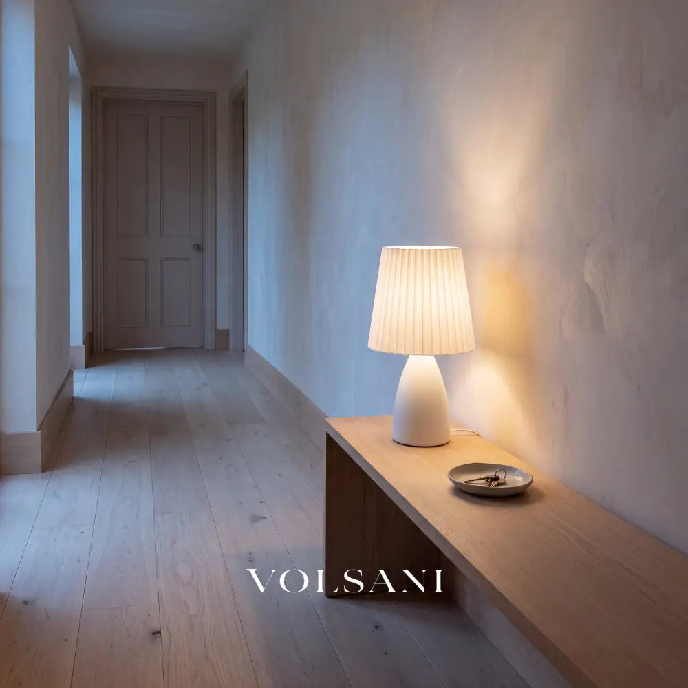 White ceramic pleated-shade lamp lit on a console in a Japandi hallway at dusk