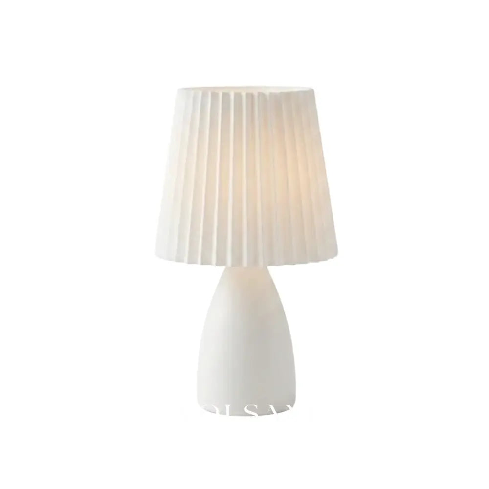White ceramic table lamp with pleated shade on a white background