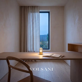 Tiny gold vintage bulb lamp lit on a desk in a Japandi home study at dusk