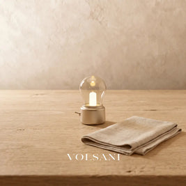 Close-up of the tiny gold vintage bulb lamp on raw oak against a plaster wall