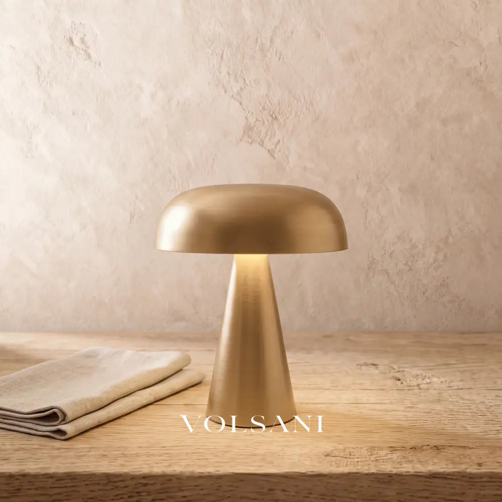 Close-up of the gold mid-century cordless lamp on raw oak against a plaster wall
