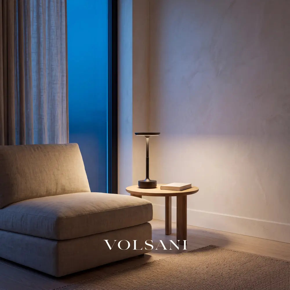 Black cordless aluminium lamp lit on a side table in a Japandi reading nook at dusk