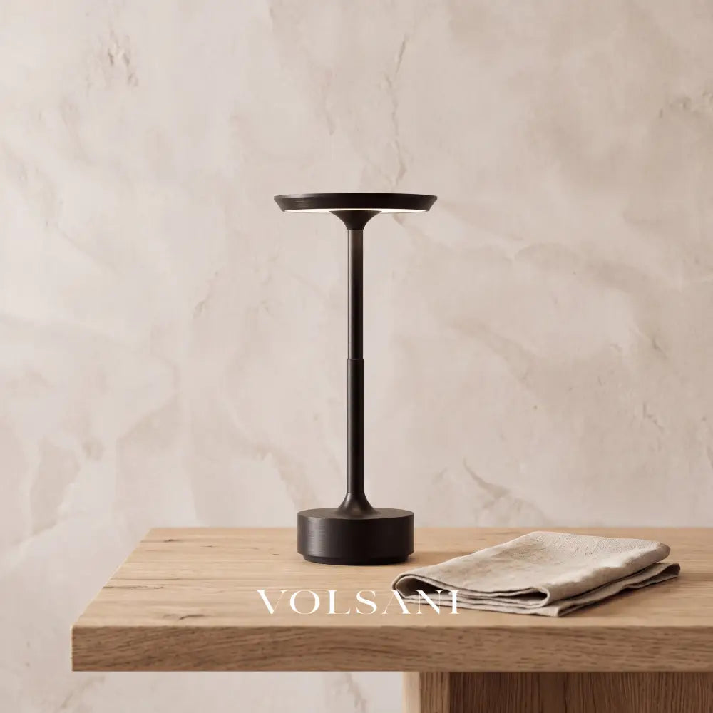 Close-up of the black cordless aluminium lamp on raw oak against a plaster wall