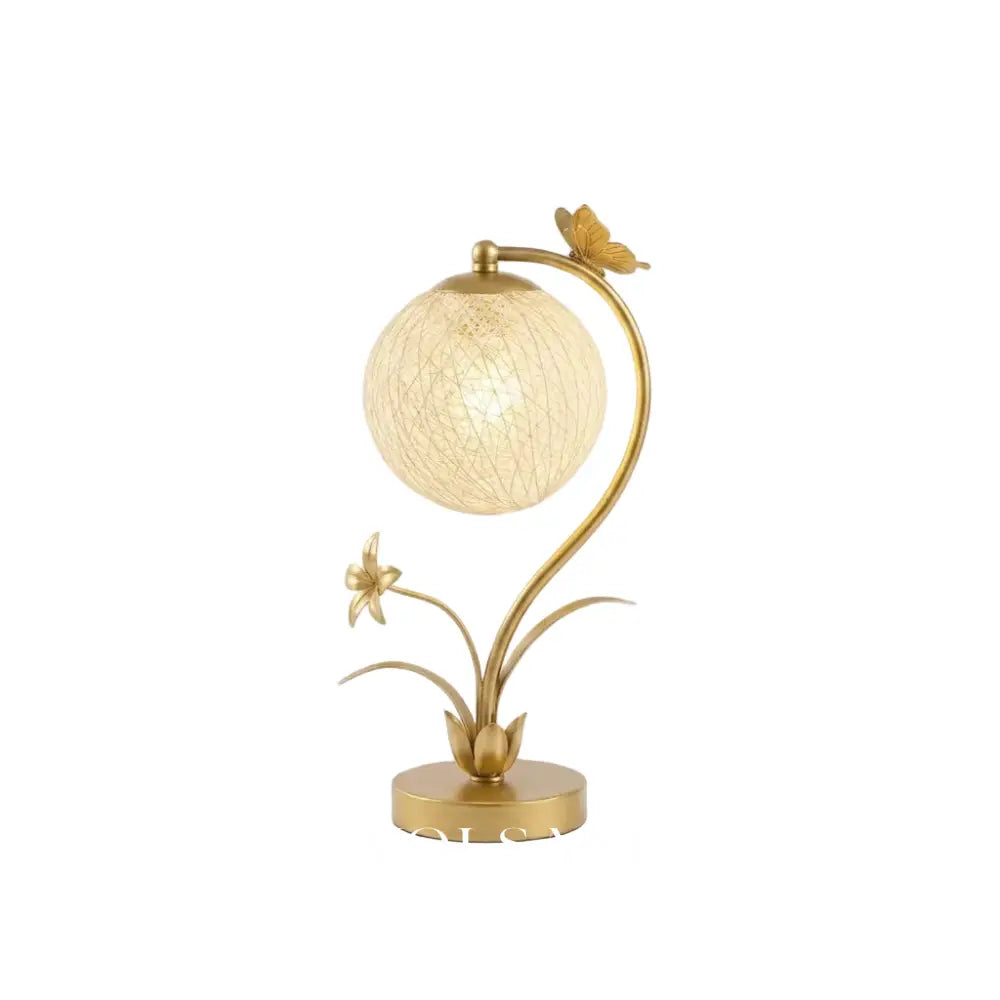 Floral table lamp with decorated glass orb on a white background