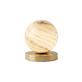 Glass globe table lamp with brass base on a white background