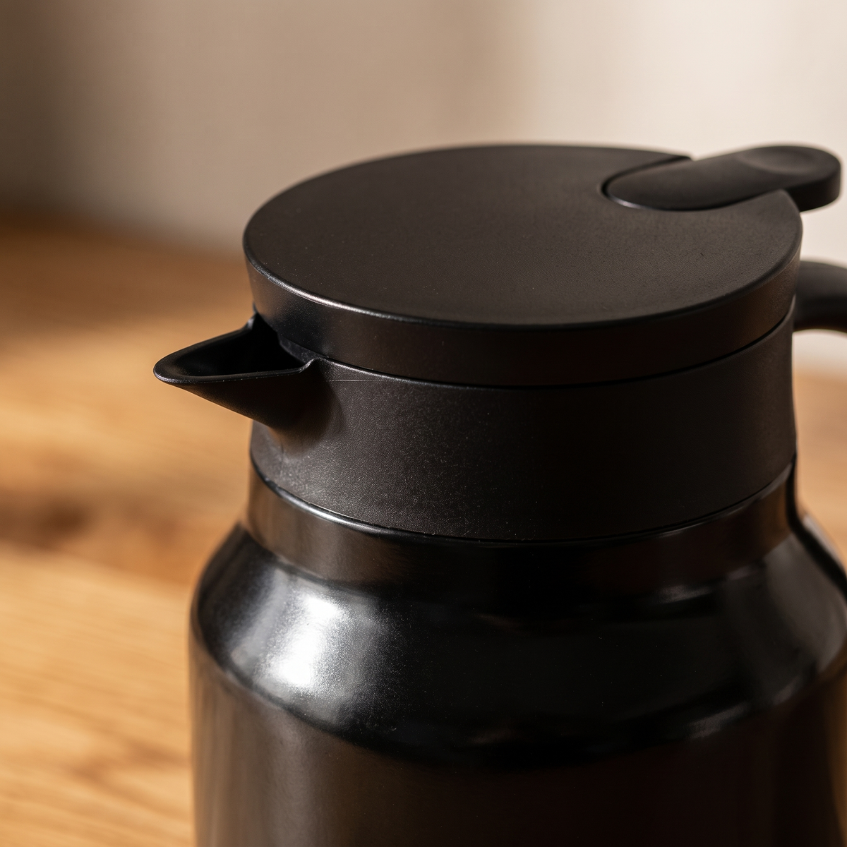 Macro detail of the black insulated teapot spout and lid seam