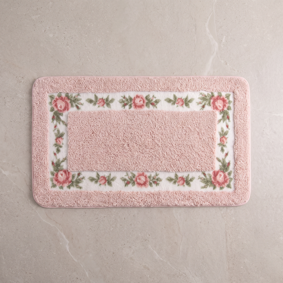 Blush Meadow floral border bath mat, overhead on stone floor