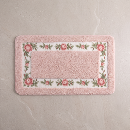 Blush Meadow floral border bath mat, overhead on stone floor