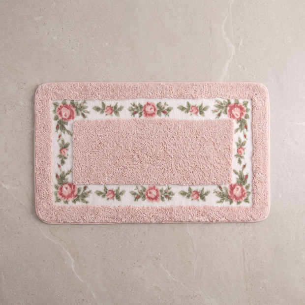 Blush Meadow floral border bath mat, overhead on stone floor