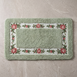 Sage Charm floral border bath mat, overhead on stone floor