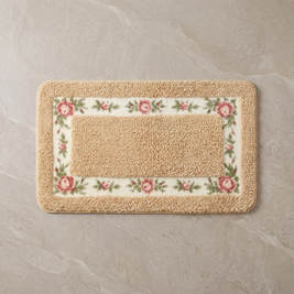 Golden Rose floral border bath mat, overhead on stone floor