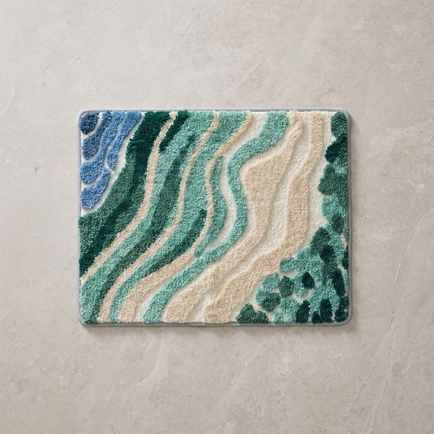 Wave pattern bath mat in blue and green, overhead on stone floor