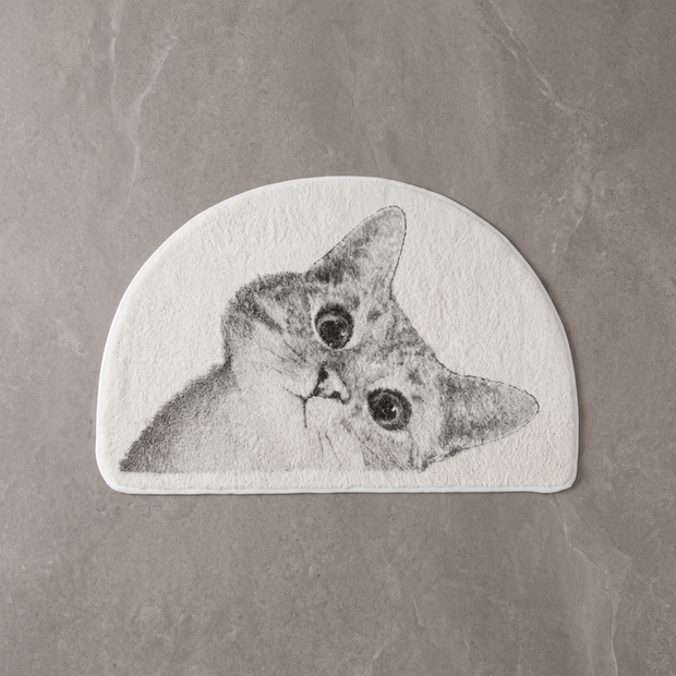 Curious Kitty cat bath mat on a pale stone floor, overhead