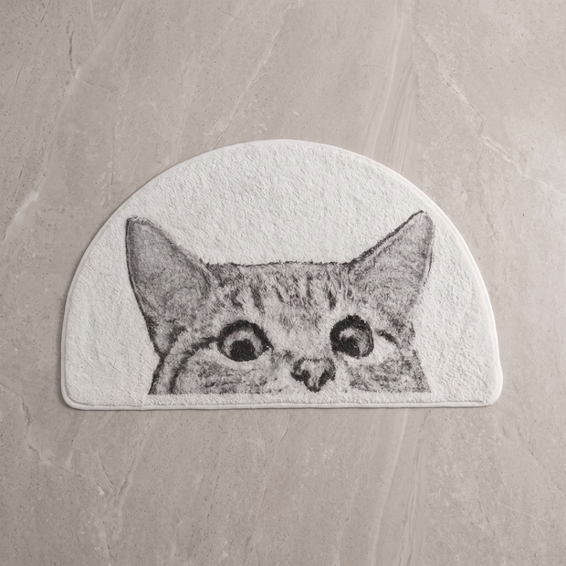 Sneaky Kitty cat bath mat on a pale stone floor, overhead
