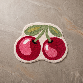 Cherry bath mat on a pale stone floor, overhead