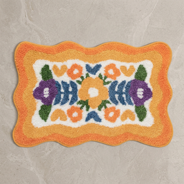 Orange colorful floral bath mat on stone floor, overhead