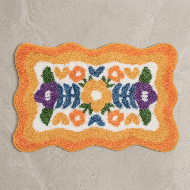 Orange colorful floral bath mat on stone floor, overhead