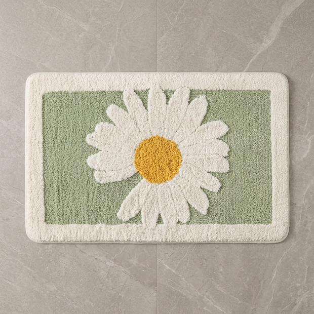 Sage Daisy plush bath mat on stone floor, overhead