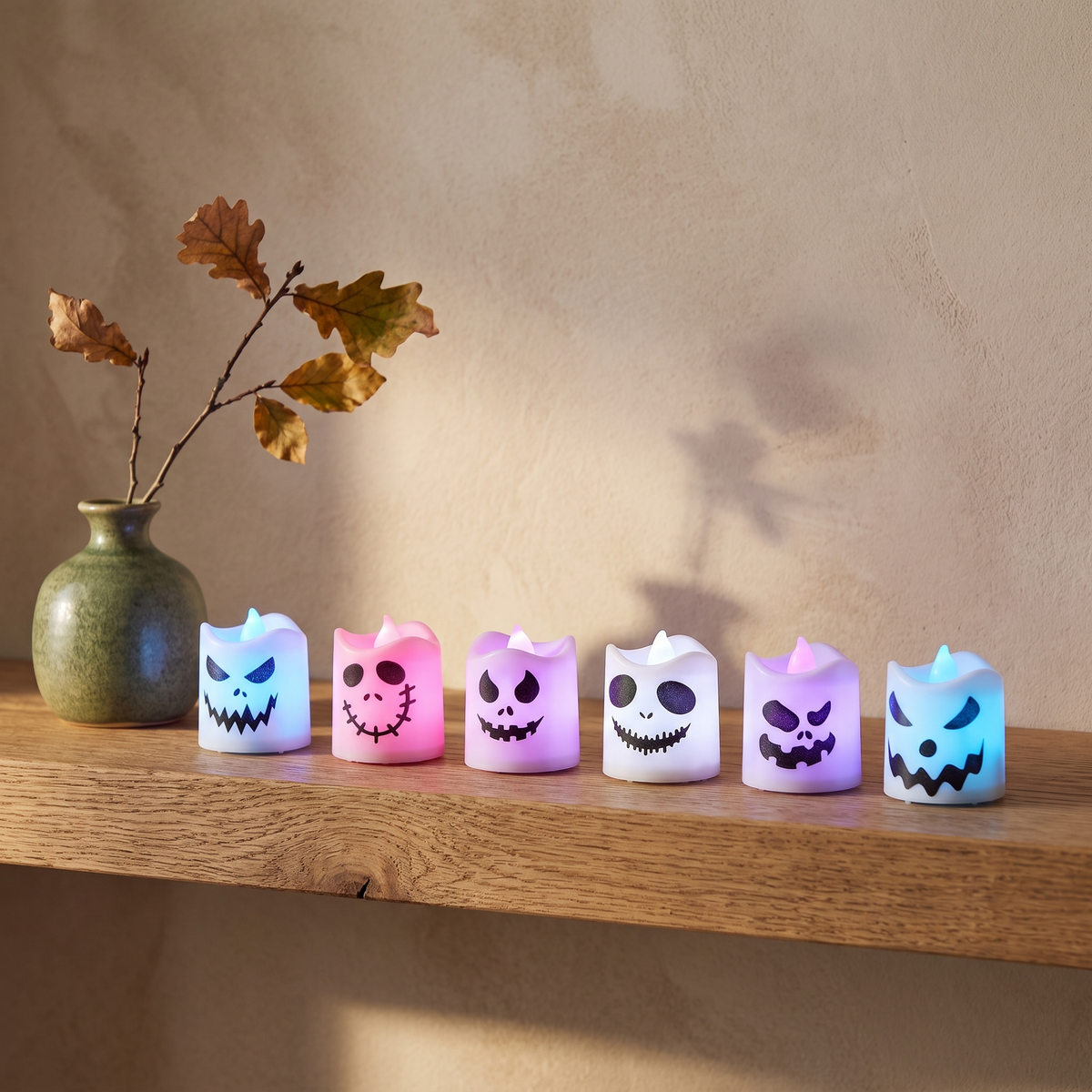 Ghost face LED tealights glowing on an oak shelf