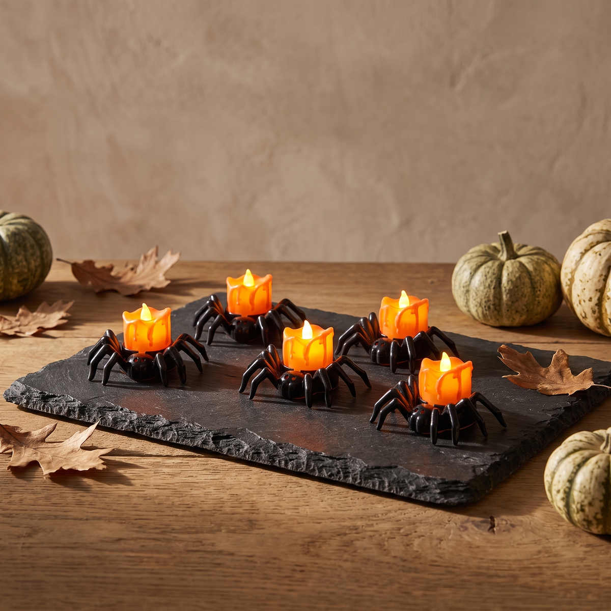 Spider LED tealights glowing on a slate tray