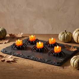 Spider LED tealights glowing on a slate tray
