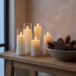 White flameless candles in clear shells on an oak console