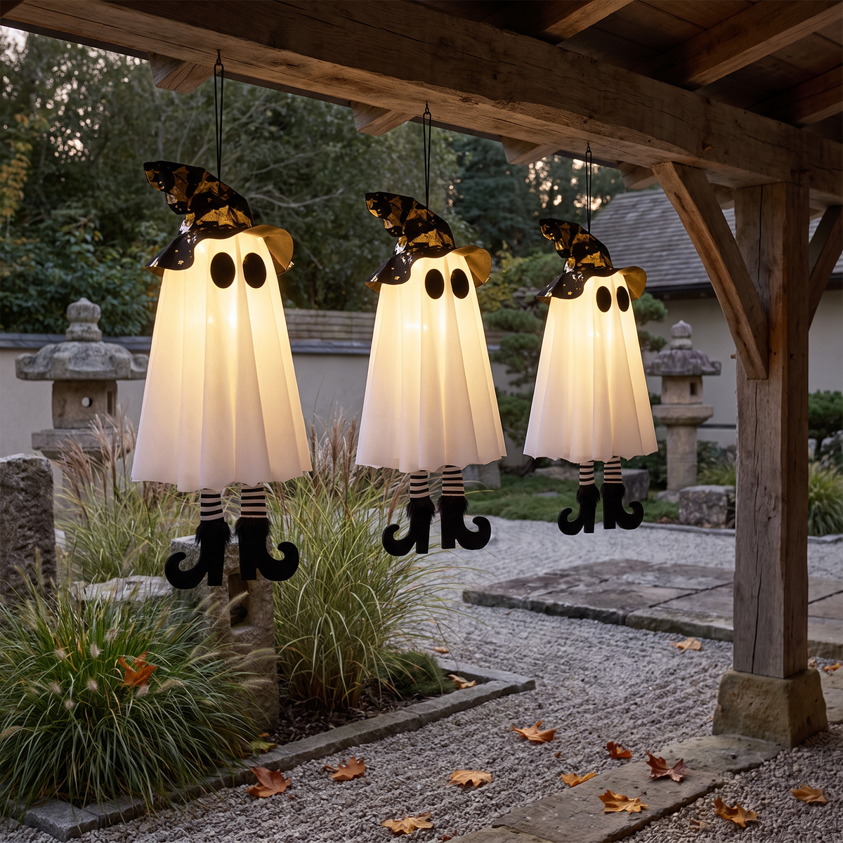 Light up witch ghosts hanging from a porch beam