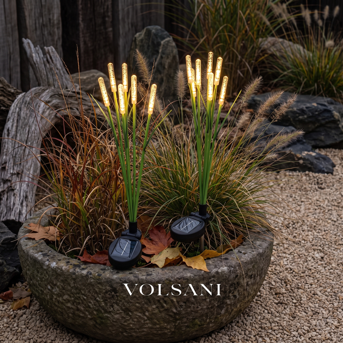 Solar reed lights glowing in a stone planter