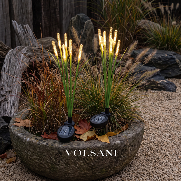 Solar reed lights glowing in a stone planter