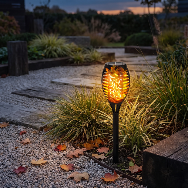 Solar flame torch light flickering in a garden bed