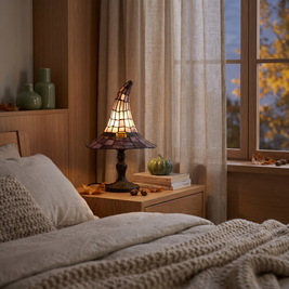 Witch hat table lamp on a bedside table at dusk