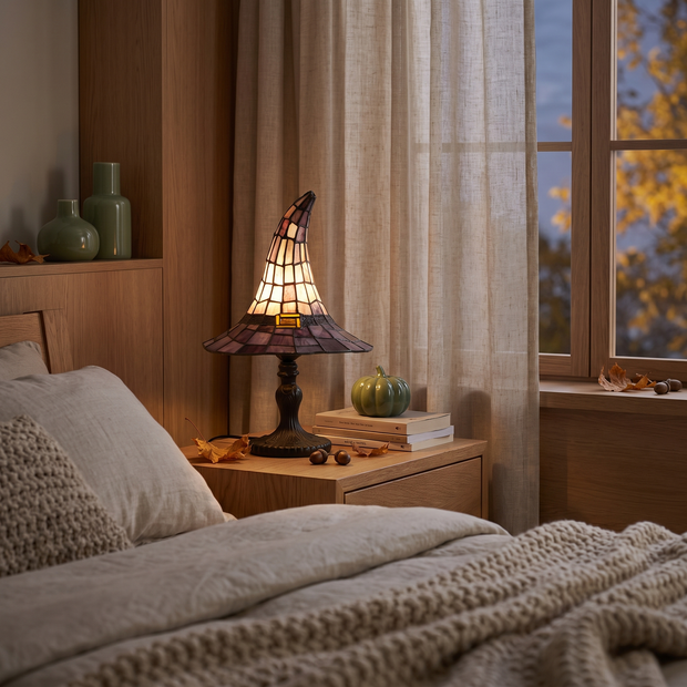 Witch hat table lamp on a bedside table at dusk