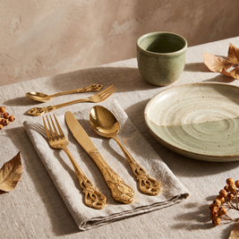 Gold baroque flatware place setting on a linen napkin