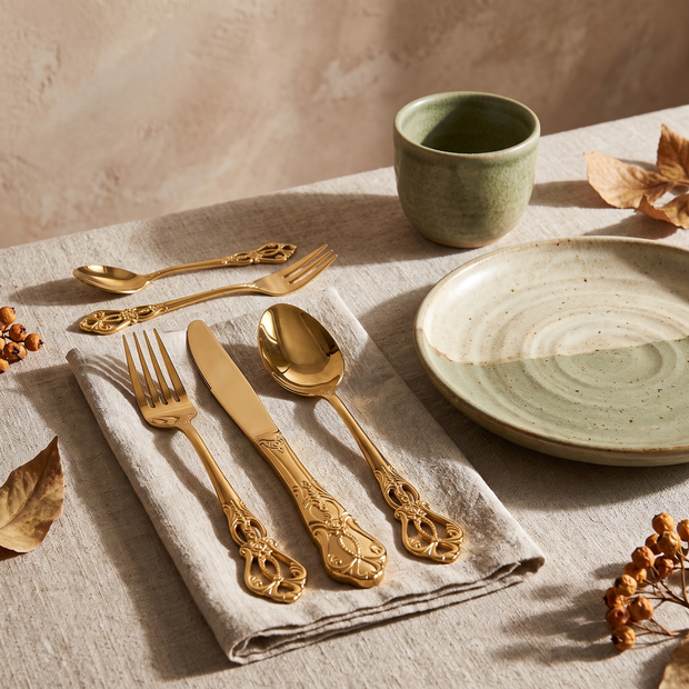 Gold baroque flatware place setting on a linen napkin