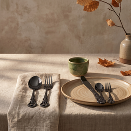 Black baroque flatware place setting on a linen napkin