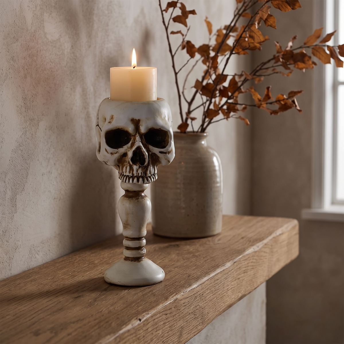 Bone white skull candle holder with a lit candle on an oak mantel