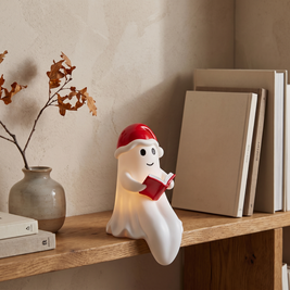 Santa hat ghost reading lamp on an oak bookshelf