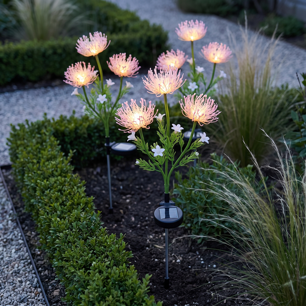 Solar flower stake lights in a garden bed at dusk