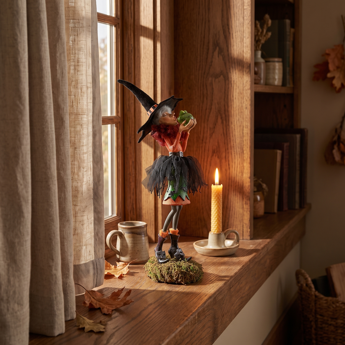 Witch figurine on a deep windowsill with a lit candle