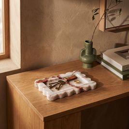 Rust scalloped marble tray with keys on an entryway console