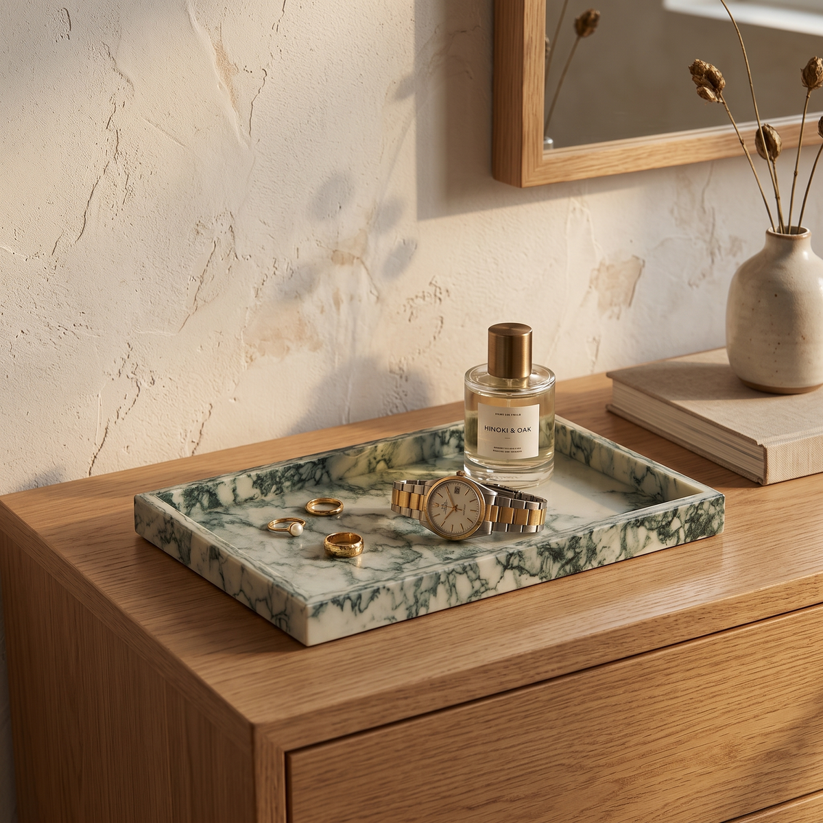 Green marble tray with rings and a watch on a bedroom dresser
