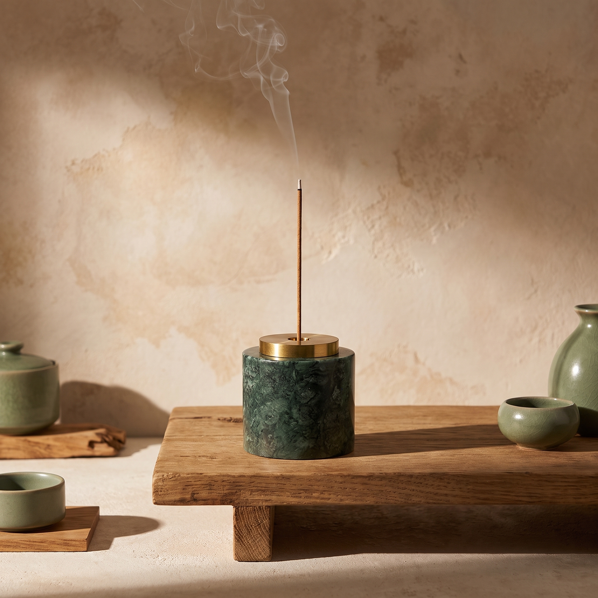Round green marble incense holder with lit incense on a meditation table
