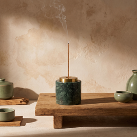 Round green marble incense holder with lit incense on a meditation table