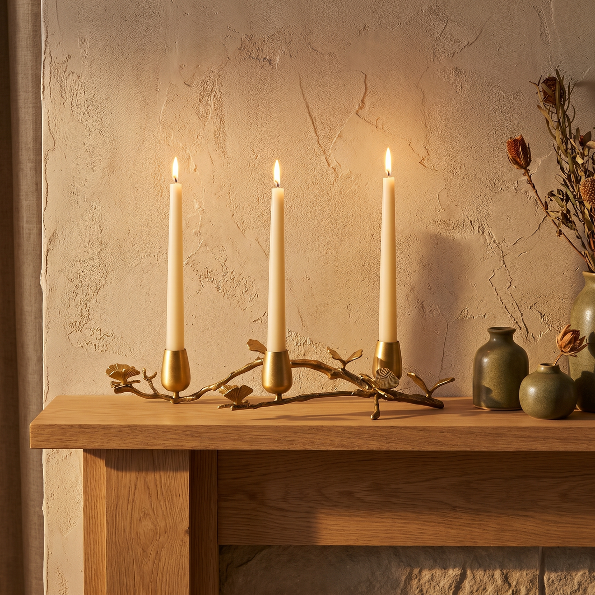 Brass ginkgo candle holder with three lit tapers on a mantel