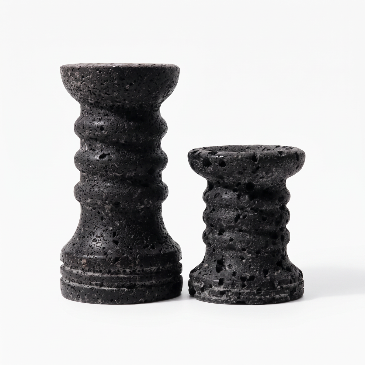 Set of two black ribbed travertine candle holders on white background