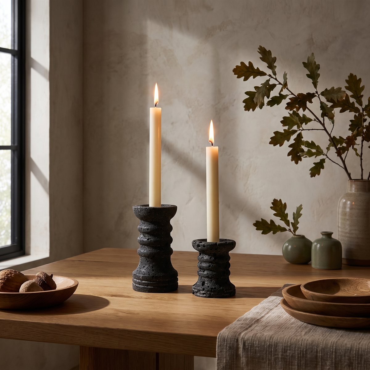 Set of two black ribbed travertine candle holders styled on an oak dining table