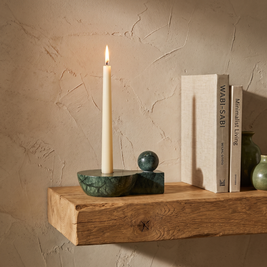 Green marble taper candle holder with sphere styled on an oak shelf beside two books