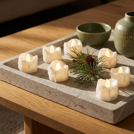 Set of flameless LED tea lights close-up, scattered on a stone tray on an oak coffee table