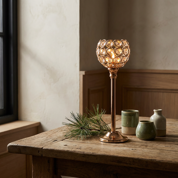 Gold crystal look beaded glass globe candle holder on a stem close-up, on an oak dining table