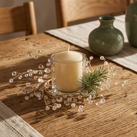 Gold branch candle ring with acrylic gems close-up, around a pillar candle on an oak table
